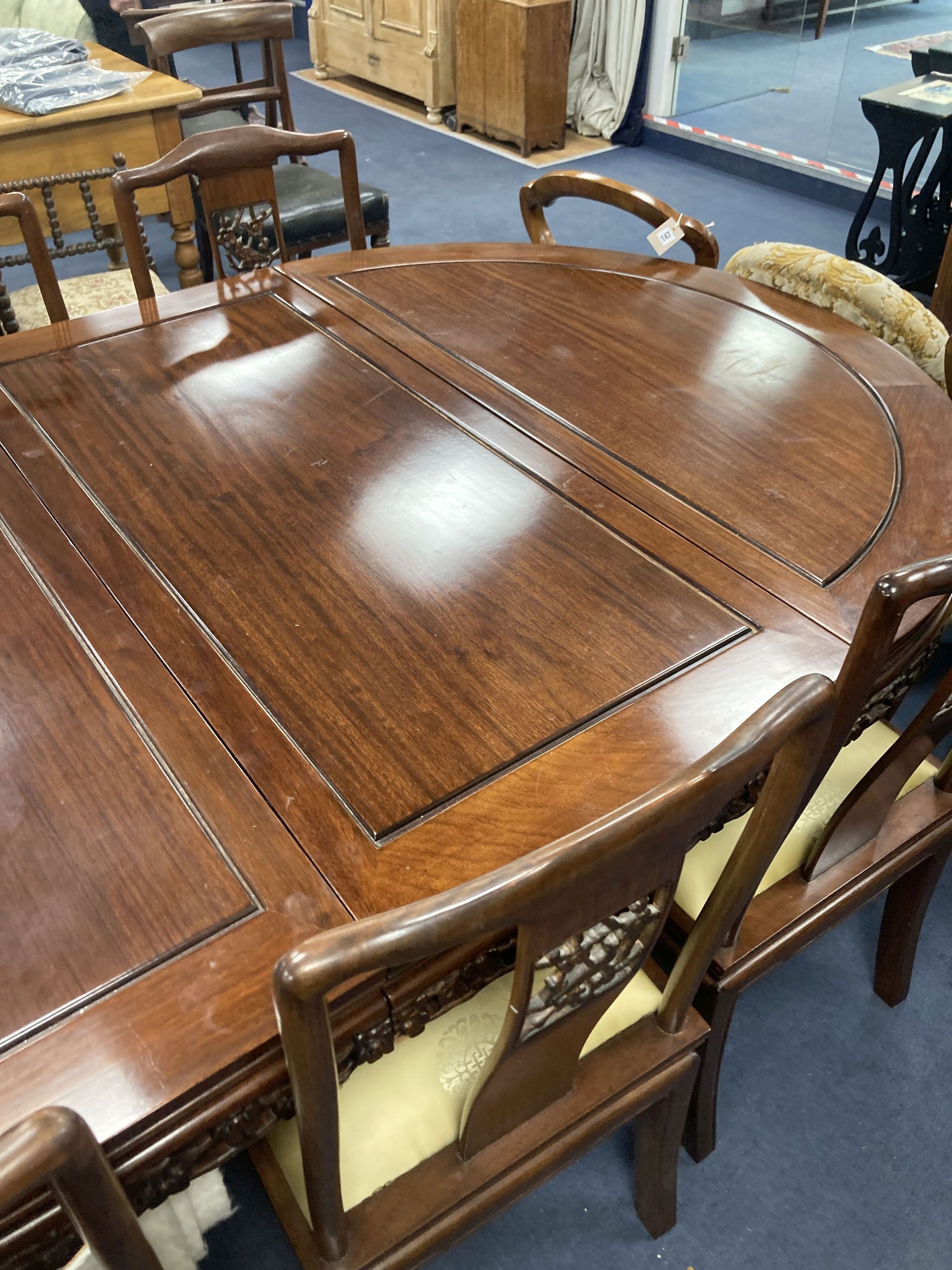 A 20th century Chinese carved hardwood dining room suite comprising sideboard fitted with four drawers above four carved panelled cupbo